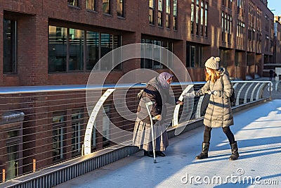 LONDON, UK â€“ Dec 13, 2018: Old beggar receiving money from a kind young woman Editorial Stock Photo